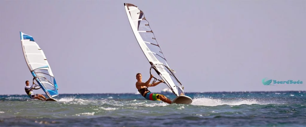 Zwei Surfer hängen im Trapez an ihrem Windsurfboard