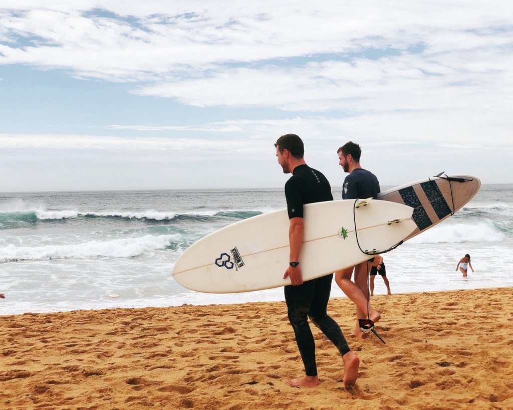 Zwei Männer gehen mit dem Surfbrett zum Wasser