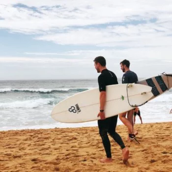 Zwei Männer gehen mit dem Surfbrett zum Wasser