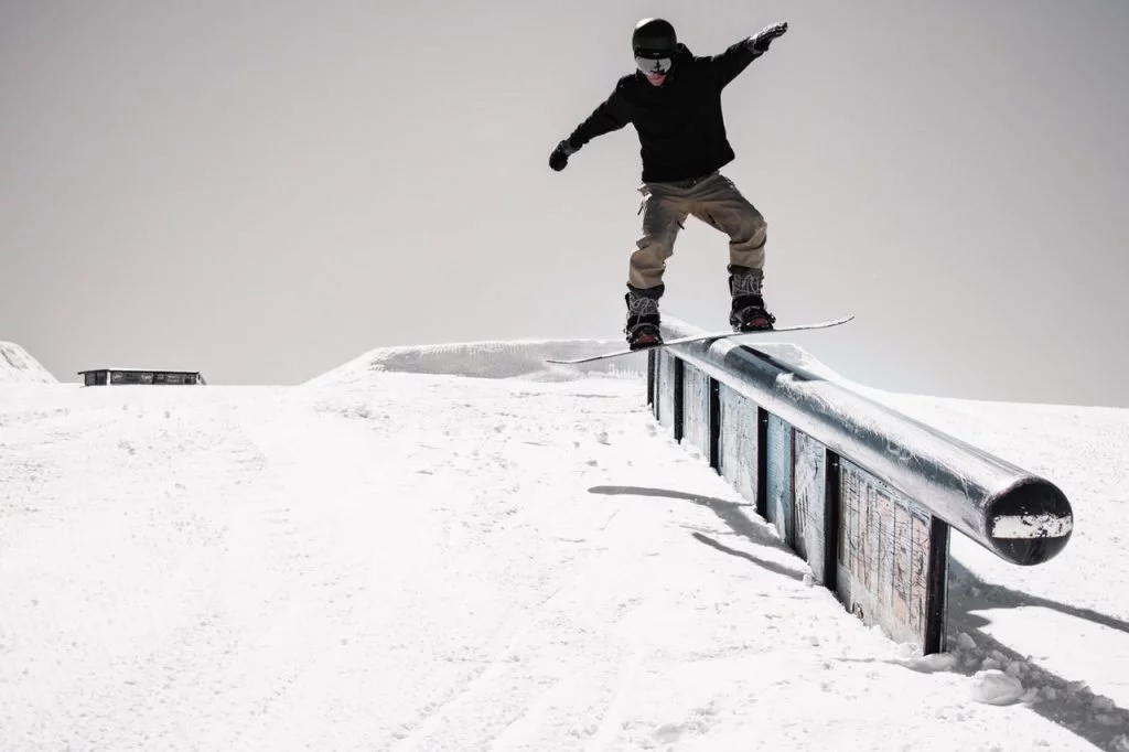Snowboarder im Park rutscht über das Rail