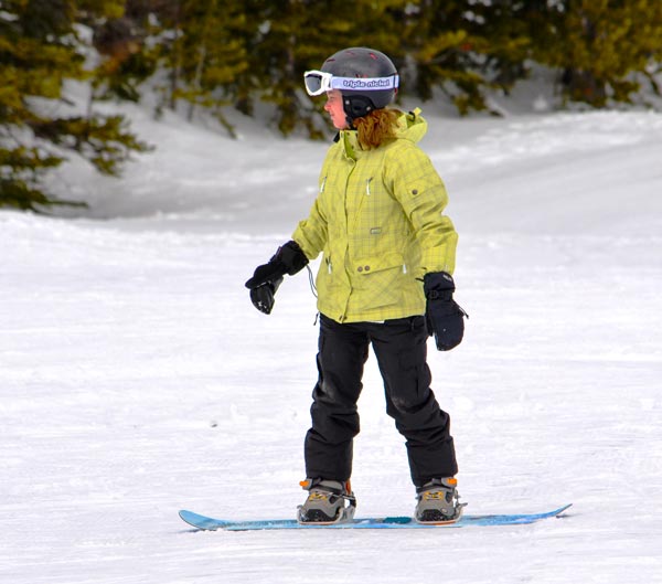 Kind mit Snowboard Ausrüstung auf der Piste